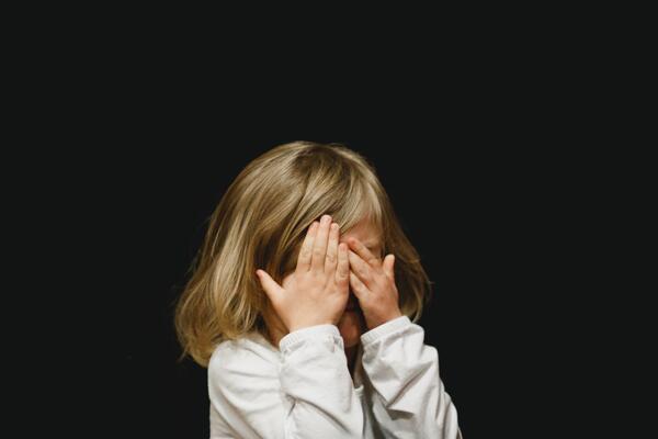 Bild vergrößern: Kind verdeckt das Gesicht mit den Händen